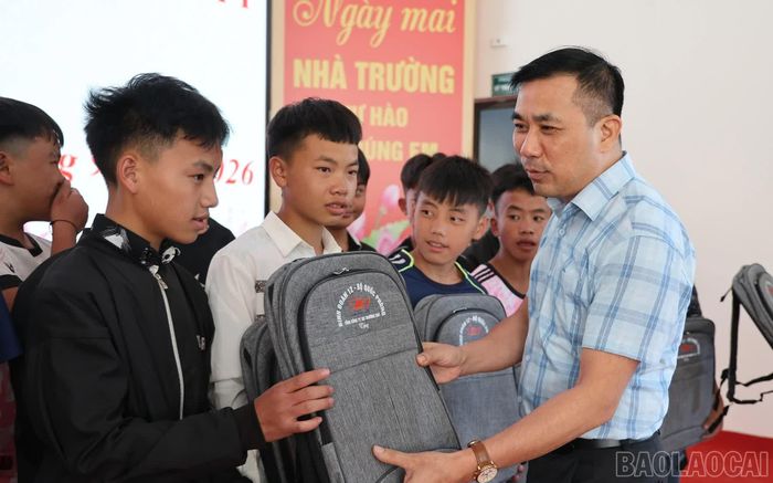 Đồng chí Nguyễn Văn Tài - Bí thư Đảng ủy xã Y Tý trao tặng cặp sách cho học sinh Trường Phổ thông nội trú tiểu học và trung học cơ sở Y Tý.