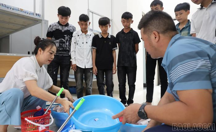 Trong phòng nội trú mới, giáo viên hướng dẫn học sinh và phụ huynh sắp xếp những vật dụng đầu tiên. Từ đây, trường học không chỉ là nơi học chữ mà còn là nơi ăn, ở và sinh hoạt của học sinh vùng cao trong suốt năm học.