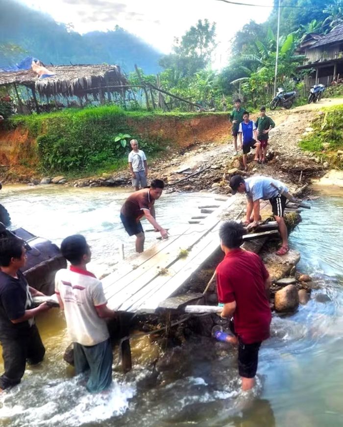 Người dân bản Na Ngân chung sức dựng lại cầu gỗ nối 2 cụm dân cư trước đó bị mưa lũ chia cắt. (Ảnh Xuân Tiến/ TTXVN).