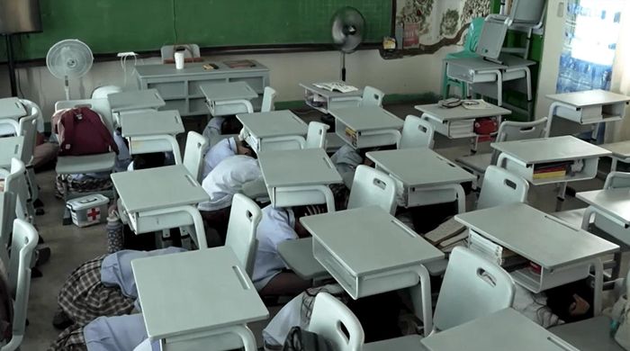 Học sinh ẩn nấp dưới bàn trong cuộc diễn tập ứng phó tình huống khẩn cấp tại trường học ở Bulacan, Philippines. Ảnh: Reuters