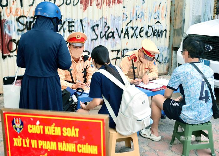 CSGT hướng dẫn người vi phạm hoàn thiện biên bản xử lý. Ảnh: T.Anh