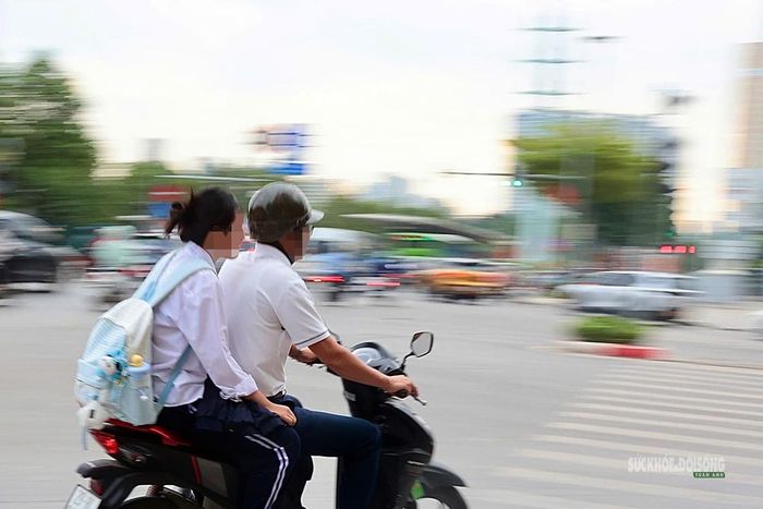 Một học sinh được người lớn chở bằng xe máy nhưng không đội mũ bảo hiểm. Ảnh: T.Anh