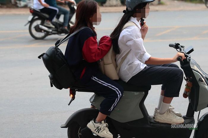 Hai học sinh đi xe máy điện, người ngồi sau không đội mũ bảo hiểm. Ảnh: T.Anh