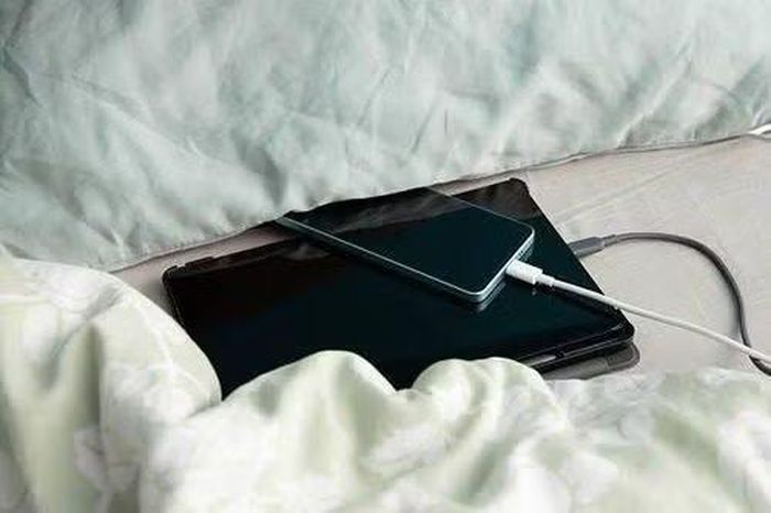 Sạc điện thoại trên giường là thói quen nhiều người mắc phải. (Ảnh minh họa từ Internet)