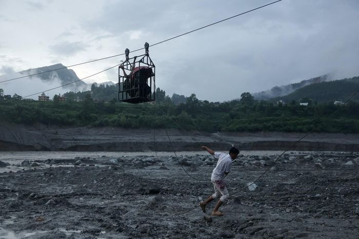  Người đàn ông dùng dây kéo tạm thời đưa người dân qua sông Trishuli từ Koloni, sau khi cầu bị hư hỏng do sạt lở, khiến nhiều người tạm thời bị cô lập tại Trishuli, huyện Nuwakot, Nepal, ngày 2/9. 