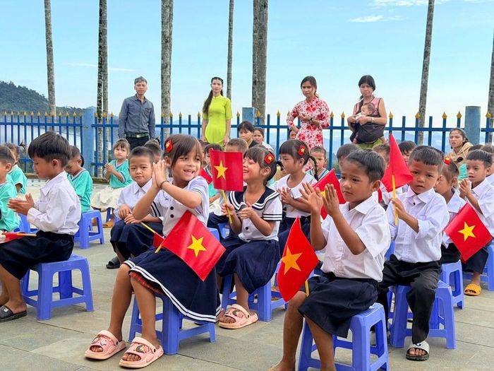 Từ sáng sớm, phụ huynh đã đưa con đến điểm trường Tắk Pổ. Một số em được người thân dìu lên những bậc thang dẫn vào trường. Trên sân trường nhỏ, cờ Tổ quốc, bóng bay được trang trí giản dị, tạo không khí tươi vui trong ngày đầu năm học