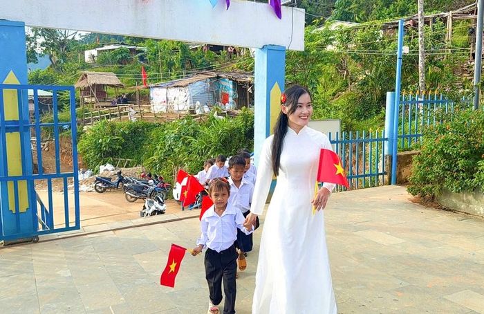 Cô giáo Trà Thị Thu nắm tay, đưa học sinh vào sân trường chuẩn bị dự lễ. Nhiều em mặc đồng phục, trên tay cầm cờ Tổ quốc. Đã có nhiều năm gắn bó với học sinh Tắk Pổ, cô Thu chứng kiến những thay đổi của điểm trường qua từng năm học