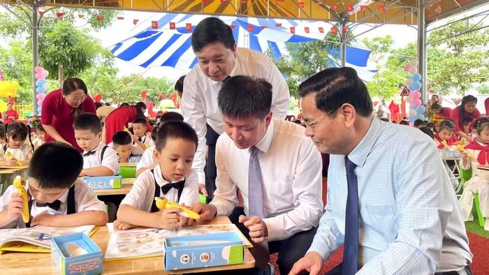 Lãnh đạo tỉnh Ninh Bình, cùng các cô giáo nhà trường hướng dẫn học sinh sử dụng bộ sách. (Ảnh: YẾN TRINH)