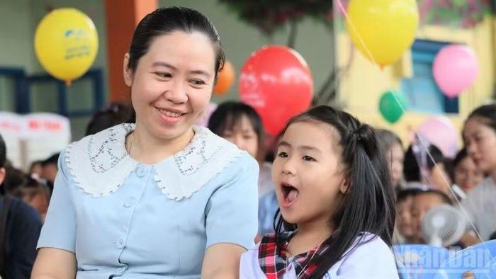 Nụ cười của bé Minh Anh cùng mẹ trong ngày khai giảng. (Ảnh: VŨ TÂN)