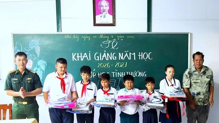 Trung tá Trần Bình Phục, Phó Đội trưởng Vận động quần chúng Đồn Biên phòng Hòn Chuối và người dân tặng quà cho các em học sinh “Lớp học tình thương” tại Lễ khai giảng năm học mới trên đảo. (Ảnh: HOÀNG TÁ)