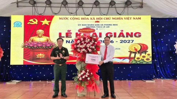 Đại tá Đinh Xuân Hùng, Chính ủy Bộ đội Biên phòng Quảng Trị tặng hoa và trao tượng trưng máy in tặng Trường trung học cơ sở Lê Lợi, xã Phong Nha (Ảnh: HG)