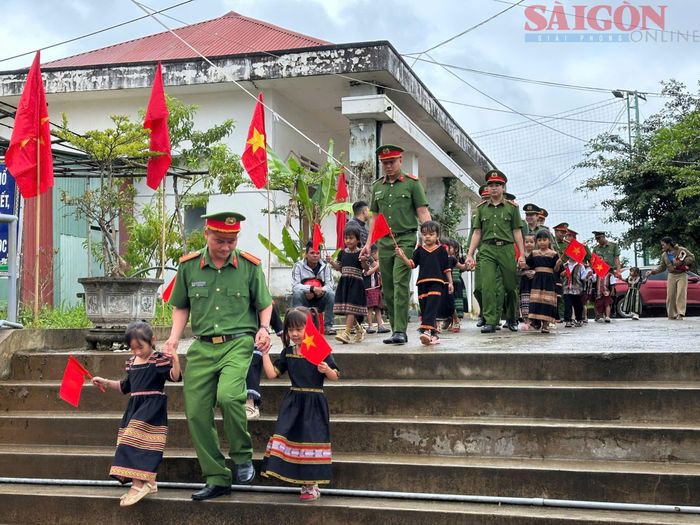  Công an xã Tu Mơ Rông đưa các em học sinh có hoàn cảnh khó khăn đến dự khai giảng tại Trường Phổ thông dân tộc bán trú Tiểu học Tu Mơ Rông. Ảnh: VƯƠNG TRẦN 