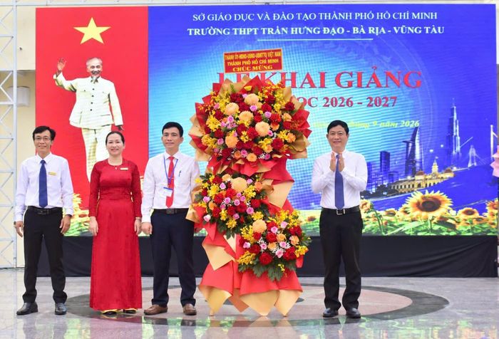 Đồng chí Võ Văn Minh tặng hoa chúc mừng lễ khai giảng tại Trường THPT Trần Hưng Đạo. Ảnh: NGUYỄN NAM