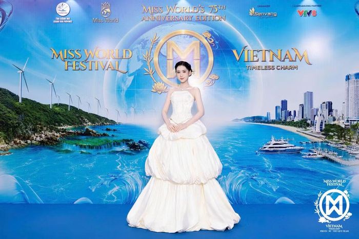 Á hậu Trương Tâm Như diện váy quây màu trắng kem với phần thân corset và chân váy xếp tầng tạo độ phồng. Thiết kế mang phom công chúa, khác với loạt váy ôm dáng xuất hiện trên thảm đỏ.