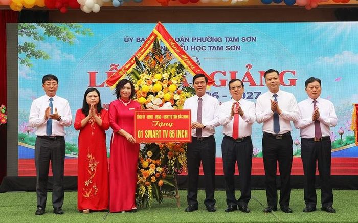 Ông Lê Xuân Lợi (thứ 4 từ phải sang trái) tặng hoa và quà cho Trường Tiểu học Tam Sơn.