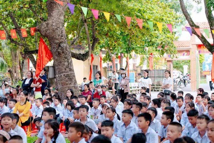 Phụ huynh tập trung phía cuối sân trường dự lễ khai giảng và ghi lại khoảnh khắc đáng nhớ của con em mình.