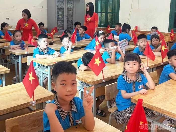 Các em học sinh Trường Tiểu học Nguyễn Trãi ngồi ngay ngắn trong không gian lớp học khang trang, rực rỡ cờ hoa, hào hứng hướng mắt lên màn hình tivi để theo dõi chương trình khai giảng chung và vẫy tay chào đón năm học mới.