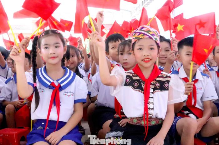 Em Lê Thị Thuỳ Chi (bìa phải) phấn khởi khi được dự lễ khai giảng trong ngôi trường mới khang trang, sạch đẹp.