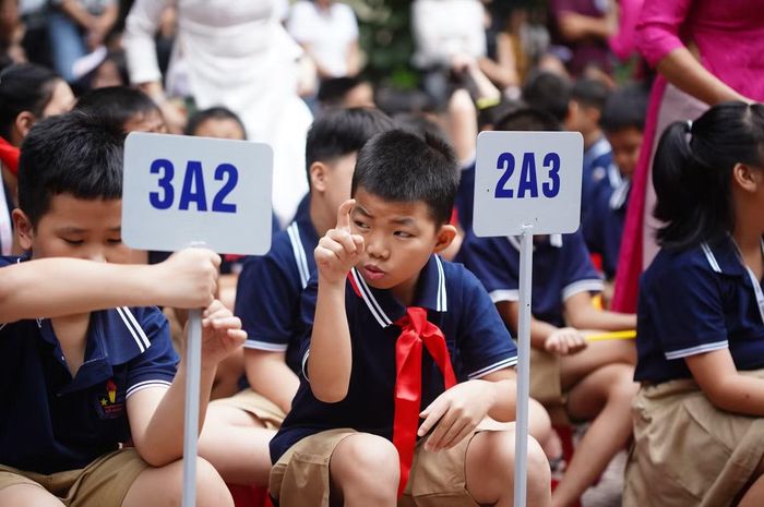 Giữa sân trường, học sinh các khối ngồi ngay ngắn theo từng hàng. Không cần nhiều lời nói, các em trò chuyện với nhau bằng những cử chỉ của đôi tay, ánh mắt và nụ cười.