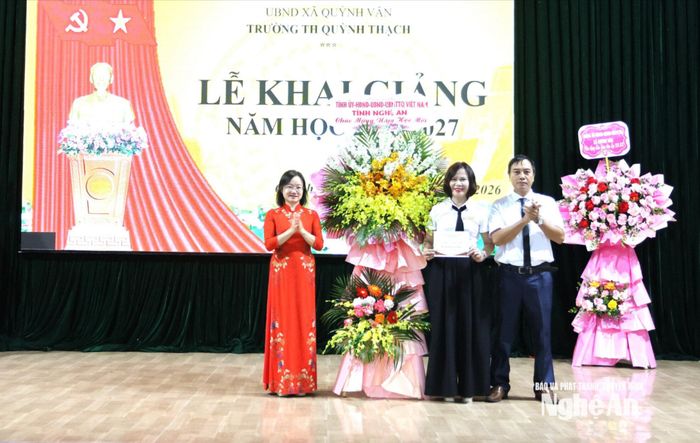 Đồng chí Thái Thị An Chung trao tặng lẵng hoa tươi thắm chúc mừng tập thể Trường Tiểu học Quỳnh Thạch. Ảnh: Như Thủy