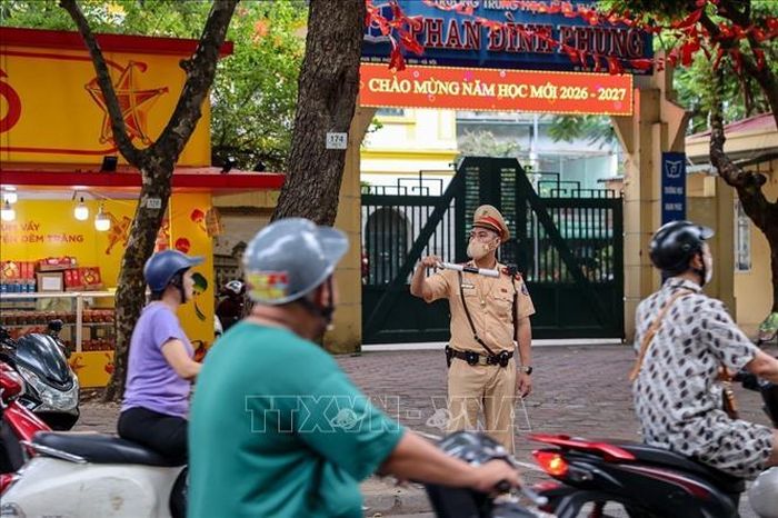 Cán bộ Đội Cảnh sát giao thông đường bộ số 2 phân luồng, hướng dẫn phương tiện trước cổng Trường Trung học phổ thông Phan Đình Phùng.