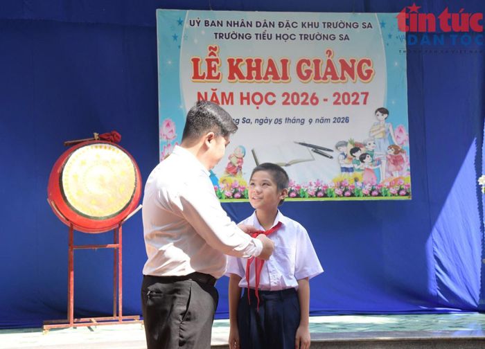 Thầy giáo Lê Xuân Hạnh trao khăn quảng đỏ cho học sinh Vi Quý Đăng.