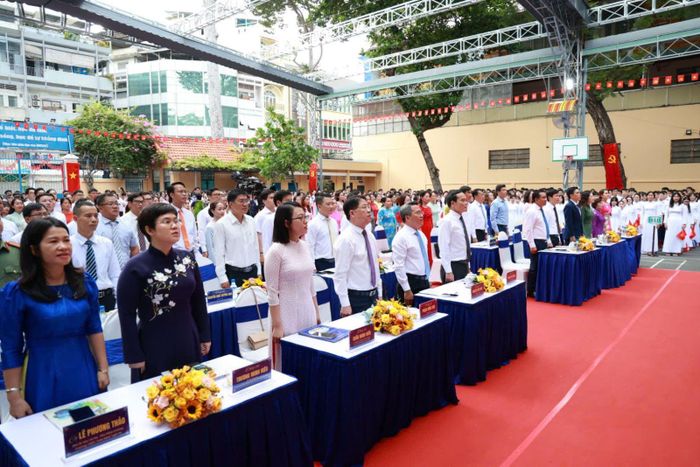 Các đại biểu và thầy cô trường THPT Trần Khai Nguyên, phường An Đông, TP Hồ Chí Minh thực hiện nghi thức chào cờ.