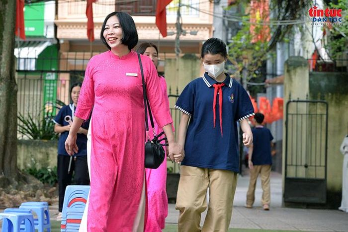 Cô giáo nắm tay học sinh đến khu vực tập trung, đồng hành cùng các em trong từng bước nhỏ đầu năm học.