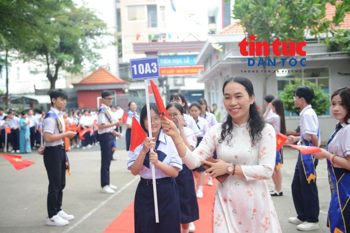 Cô giáo chủ nhiệm dẫn các em học sinh khối 10 tiến vào trường trong ngày khai giảng.