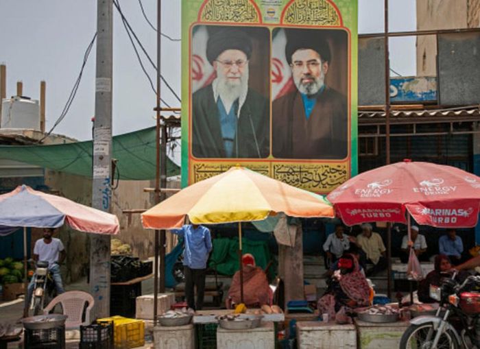 Người bán hàng ở Tehran bên dưới poster hình cố Lãnh tụ Ali Khamenei và Lãnh tụ đương nhiệm Mojtaba Khamenei. Ảnh: Jerusalem Post