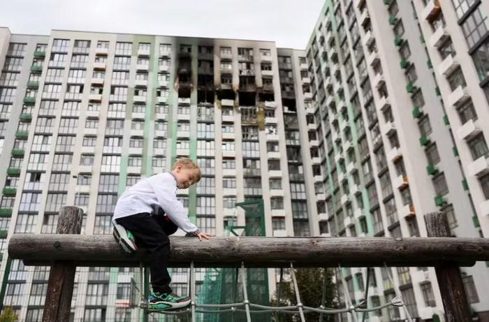 Svyatoslav, 6 tuổi, bắt đầu học lớp một trường tiểu học, ngồi trước một tòa nhà chung cư bị hư hại do cuộc tấn công bằng máy bay không người lái của Nga, tại Kiev, Ukraine ngày 1/9. Ảnh: Reuters.