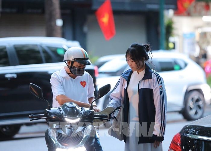 Nữ sinh lớp 10 Trường THPT Việt Đức được bố đưa đến trường từ sớm để dự Lễ khai giảng đầu tiên ở ngôi trường mới. Ảnh: Hoàng Hiếu - TTXVN