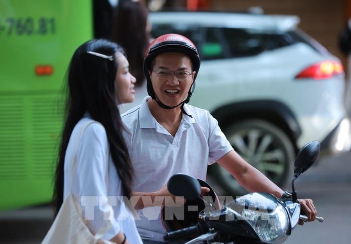 Nữ sinh lớp 10 Trường THPT Việt Đức được bố đưa đến trường từ sớm để dự Lễ khai giảng đầu tiên ở ngôi trường mới. Ảnh: Hoàng Hiếu - TTXVN