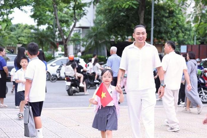 Bàn tay bé nhỏ siết chặt lấy tay bố giữa sân trường rộn rã cờ hoa. Hòa vào dòng người nhộn nhịp của ngày hội tựu trường, em tò mò ngước nhìn xung quanh, bắt đầu những bước chân đầu đời tại mái trường mới.