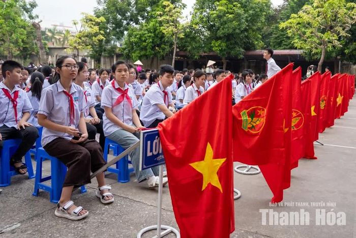 Sân trường ngập sắc trắng của đồng phục học sinh, sắc đỏ của khăn quàng và màu xanh của hàng cây.