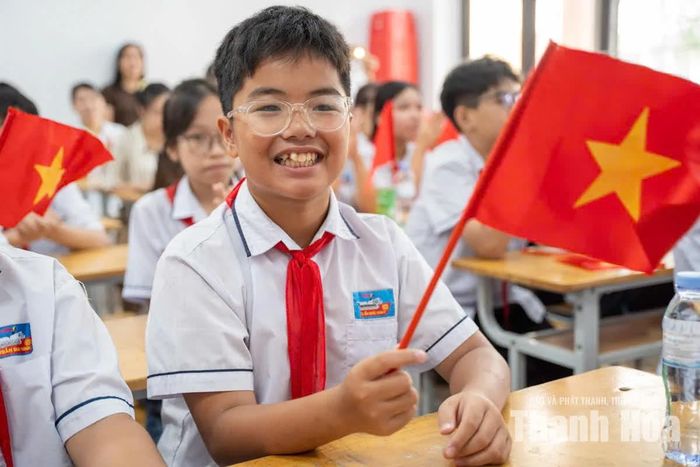 Học sinh hào hứng cầm cờ Tổ quốc trong lớp học, chờ đón khoảnh khắc tiếng trống khai giảng năm học mới vang lên.