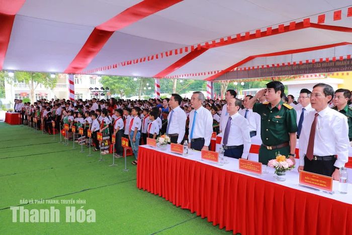 Các đại biểu và thầy, cô giáo cùng học sinh thực hiện nghi lễ chào cờ.