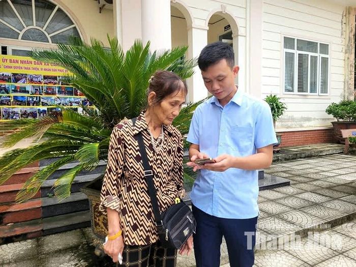 Anh Hà Thái Huy, Bí thư chi bộ thôn Liên Sơn, xã Cẩm Thạch hướng dẫn người dân sử dụng dịch vụ công trực tuyến trên điện thoại di động.