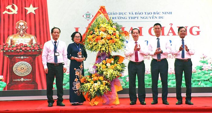  Đồng chí Nghiêm Xuân Hưởng và các đại biểu tặng hoa chúc mừng nhà trường. 