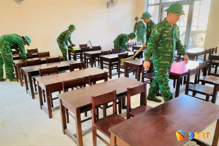 Cán bộ, chiến sĩ Đồn Biên phòng Đắc Pring hỗ trợ lau dọn, xếp ngay ngắn bàn ghế học sinh tại điểm Trường Phổ thông nội trú Tiểu học và THCS Đắc Pring. Ảnh: THÁI TÙNG