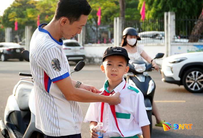Phụ huynh sửa soạn áo quần tươm tất cho con. Ảnh: HỒ QUÂN