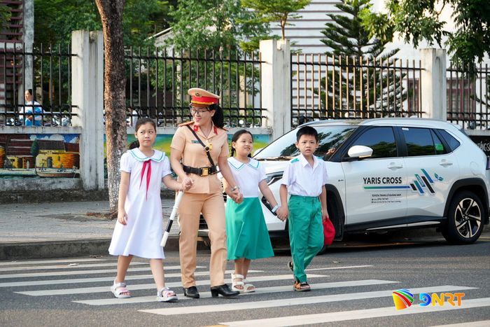 Cảnh sát giao thông hỗ trợ đưa học sinh sang đường. Ảnh: HỒ QUÂN