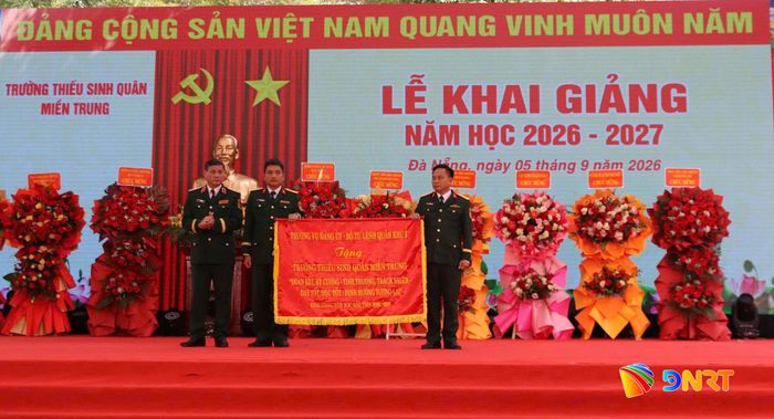 Trung tướng Lê Ngọc Hải, Tư lệnh Quân khu 5 (ngoài cùng bên trái) tặng bức trướng cho Trường Thiếu sinh quân miền Trung. Ảnh: NGÂN BÌNH