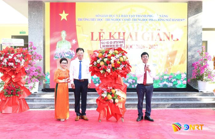 Trưởng ban Nội chính Thành ủy Võ Công Chánh (bên phải) tặng hoa chúc mừng nhà trường. Ảnh: NGỌC HÀ