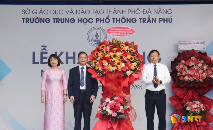 Trưởng ban Tổ chức Thành ủy Đoàn Duy Tân (bên phải) tặng hoa chúc mừng thầy và trò Trường THPT Trần Phú nhân dịp khai giảng năm học mới. Ảnh: KHÁNH NGÂN