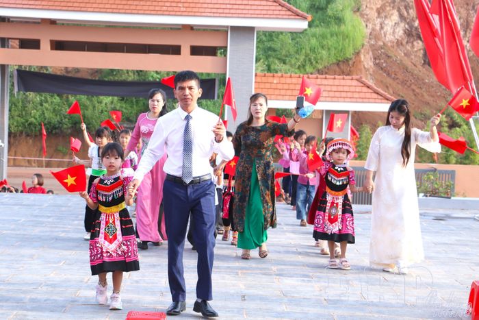 Thầy Hiệu trưởng cùng giáo viên chủ nhiệm đón các em học sinh lớp 1 vào trường.