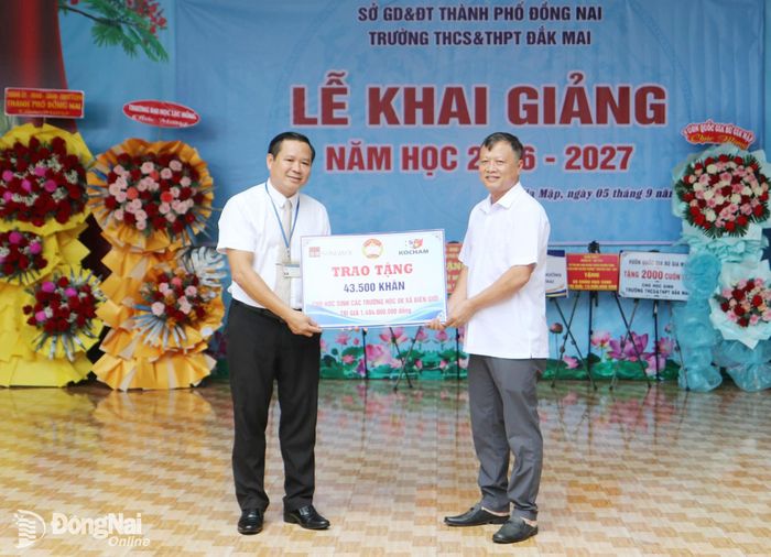 Phó Chủ tịch Ủy ban MTTQ Việt Nam thành phố Đồng Nai Nguyễn Tấn Phú thay mặt nhà tài trợ trao bảng biểu trưng tặng 43,5 ngàn khăn cho đại diện Trường THCS-THPT Đắk Mai tại lễ khai giảng. Ảnh: Văn Truyên