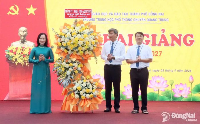 Ủy viên Ban Thường vụ Thành ủy, Bí thư Đảng ủy, Chủ tịch HĐND phường Bình Phước Giang Thị Phương Hạnh tặng lẵng hoa của Thành ủy, HĐND, UBND, Ủy ban MTTQ Việt Nam thành phố cho Trường THPT chuyên Quang Trung. Ảnh: Quang Minh