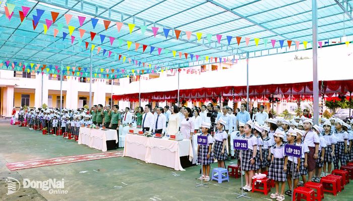 Các đại biểu và giáo viên, học sinh thực hiện nghi thức chào cờ tại buổi lễ. Ảnh: Như Tình