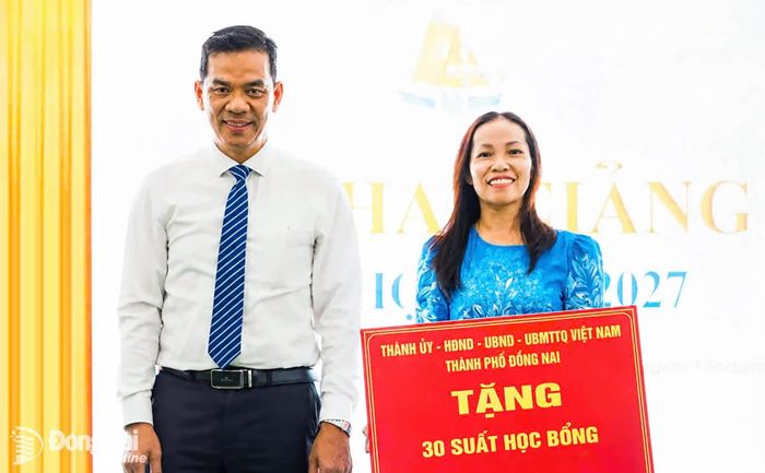 Ủy viên Ban Thường vụ Thành ủy, Chủ nhiệm Ủy ban Kiểm tra Thành ủy Trần Trung Nhân trao bảng biểu trưng tặng học bổng cho nhà trường. Ảnh: Vương Thế